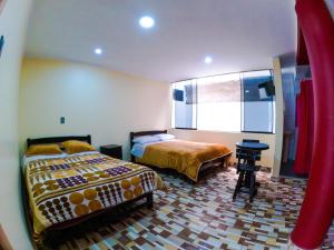 a bedroom with two beds and a desk and a window at Hotel Sol de Oro Ayacucho in Ayacucho