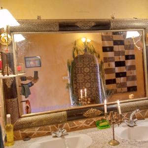 a mirror above a bathroom sink with two candles at Dar adiafa dar asalam in Aït Benhaddou