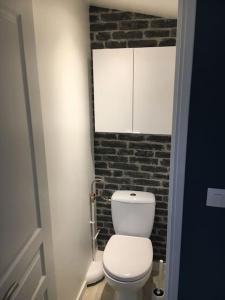 een badkamer met een wit toilet en een bakstenen muur bij Suite atypique de qualité in Orsay