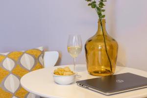 a table with a glass of wine and a laptop and a vase at Sweet Home Graziella vicino stazione Bologna per 6 persone in Bologna