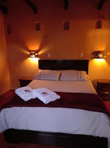 a bedroom with a bed with two towels on it at Hotel Calicanto Real Cafe Museo in Monguí