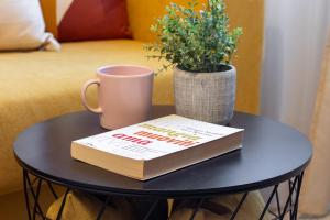 a book on a table with a mug and a plant at Sweet Home Graziella vicino stazione Bologna per 6 persone in Bologna