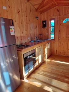 una cucina con frigorifero in acciaio inossidabile e piano cottura di Cabaña Queltehue Cochamó a Cochamó