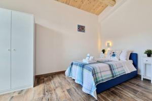 una camera da letto bianca con un letto blu con una coperta di Lí da Ste a Ripatransone