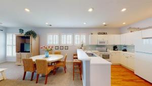 une cuisine avec une table et des chaises et une cuisine avec des placards blancs dans l'établissement Litchfield Beach Retreats 2BR Scenic Balcony Views, à Pawleys Island