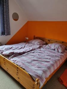 an unmade bed in a bedroom with an orange wall at Haus an der Drau in Feistritz im Rosental