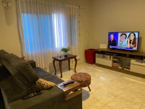 sala de estar con sofá y TV de pantalla plana en Quarto no Ap do Roberto Centro en Jaraguá do Sul