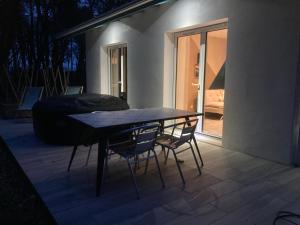 un tavolo e due sedie su un patio di notte di Gîte du Pin avec Spa privatif a Pey Altre 3 foto
