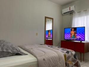 a bedroom with a bed and a flat screen tv at Quarto no Ap do Roberto Centro in Jaraguá do Sul