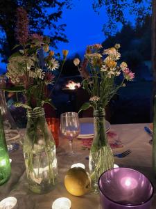 einen Tisch mit zwei Vasen mit Blumen und einem Weinglas in der Unterkunft Plasur - Apartement Bella Vista in Montechiaro