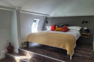a bedroom with a bed with red and yellow pillows at Sgwâr in Menai Bridge