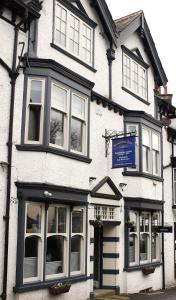 a white building with a blue sign on it at Bowness Bay Suites in Bowness-on-Windermere