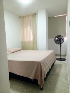 a bedroom with a white bed and a fan at Cali Sur Centrar Apto 2 - Somos Pet Friendly in Cali