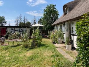 een huisje met een tuin met een tafel en een parasol bij Cosy country house in Nysted