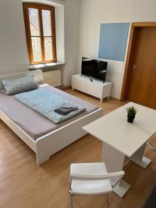 een slaapkamer met een bed en een tafel en een televisie bij Privatzimmer im Herzen von Iphofen in Iphofen
