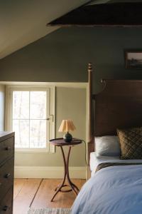 een slaapkamer met een bed en een tafel met een lamp bij Serene Estate - Heated Saltwater Pool, Sauna, 5 Mins to Hudson in Catskill