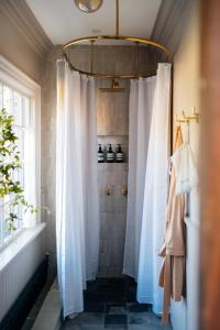 een badkamer met een douche en witte gordijnen bij Serene Estate - Heated Saltwater Pool, Sauna, 5 Mins to Hudson in Catskill