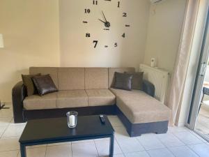 a living room with a couch and a clock on the wall at Nav Apart, Salamina in Paloúkia