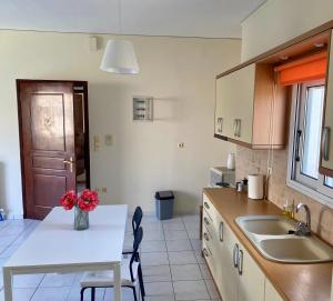 a kitchen with a table with a vase of flowers on it at Nav Apart, Salamina in Paloúkia