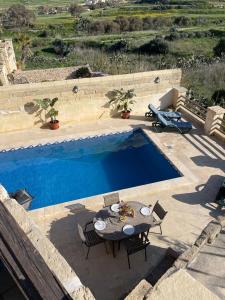 una mesa y sillas junto a una piscina en Soluna Boutique Guesthouse, en Għasri