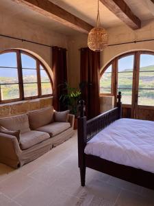 1 dormitorio con cama, sofá y ventanas en Soluna Boutique Guesthouse, en Għasri