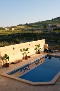 una piscina con macetas junto a una pared en Soluna Boutique Guesthouse, en Għasri