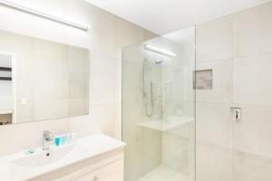 y baño blanco con lavabo y ducha. en Sensational Rest in the North, en Auckland