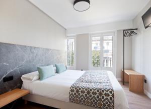 una camera da letto con un grande letto bianco con cuscini blu di PR 25 de Julio a Santiago de Compostela