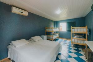 1 dormitorio con cama blanca y pared azul en Pousada Cidreira en Morretes