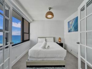 Dormitorio blanco con cama y ventana grande en Cozy Beachfront Condo w Beach Service 1410, en Miami Beach