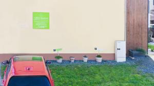 ein rotes Auto, das neben einer Wand mit Topfpflanzen parkt in der Unterkunft Erfblick-Apartments in Eichenbühl