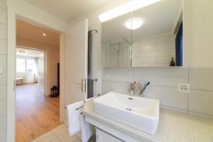 Baño blanco con lavabo y espejo en Lisighaus en Wildhaus