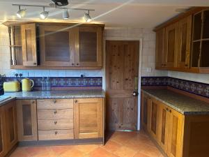 een keuken met houten kasten en granieten aanrechtbladen bij Trowbridge Lodge in Trowbridge