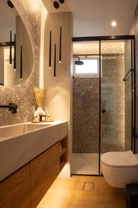 een badkamer met een douche, een wastafel en een toilet bij Tommy's Family Apartment in Kateríni