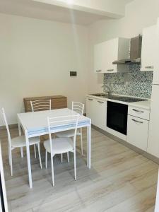 a white kitchen with a white table and chairs at Rent House Scauri in Minturno
