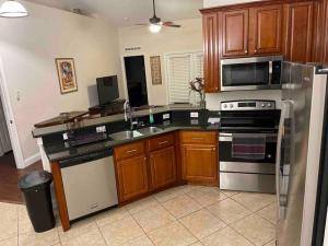 eine Küche mit Holzschränken und Küchengeräten aus Edelstahl in der Unterkunft Orlando 4 BR Home Centrally Located on Dead End St in Orlando