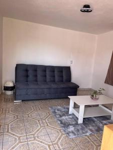 sala de estar con sofá negro y mesa en Departamento Zaragoza, en Chignahuapan