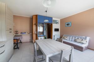 a kitchen and living room with a table and a couch at Casa Acqua Marina vicino al mare con parcheggio privato in Quartu SantʼElena