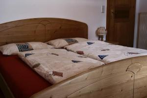 a bed with a wooden frame with two pillows on it at Ausser Brugghof in Senales