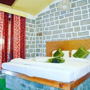 Ce lit se trouve dans une chambre dotée d'un mur en briques. dans l'établissement Hotel Seraj International , Aleo Hill View, à Manali