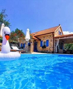 a swan float in a swimming pool next to a house at Holiday Home Toma in Puljane