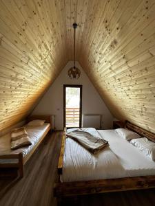 two beds in a large room with wooden ceilings at Art Resort in Peje