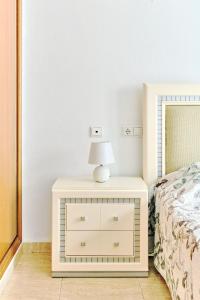 uma mesa de cabeceira branca com um candeeiro ao lado de uma cama em Palacio Del Mar em Torrevieja