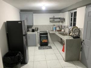 a kitchen with a refrigerator and an oven in it at Cozy 2 bed in Ocho Rios in Ocho Rios +4 photos