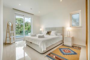 a white bedroom with a bed and a large window at Casa Lilou - Luxury Oceanview Penthouse in Lagos +45 photos
