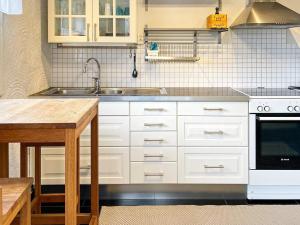 a kitchen with white cabinets and a sink and a table at Holiday home BÅSTAD II in Båstad