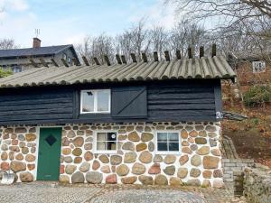 una pequeña casa de piedra con una puerta verde en Holiday home BÅSTAD II, en Båstad