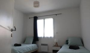 a bedroom with two beds and a window at L'Olivier in Montoison