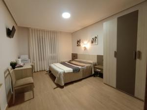 Habitación de hotel con cama y silla en Habitaciones Javier LVI 0006 en Vitoria-Gasteiz