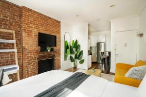 - une chambre avec un mur en briques, un lit et une cheminée dans l'établissement 24-4 New Private Terrace W D Apt Prime Gramercy, à New York